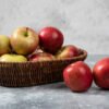 Wicker basket of red juicy apples on marble surface GRANNY SMITH APPLE
